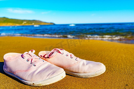 运动鞋摄影照片_沙滩上的女运动鞋。在海边散步...女运动鞋在沙滩