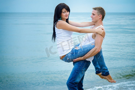 穿着牛仔裤和白色T恤的一男一女在海边