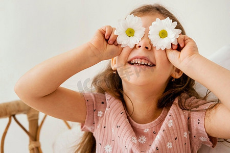 微笑的小女孩玩春天的花覆盖她的眼睛