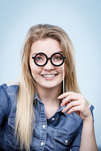 快乐的女人拿着假眼镜玩得很开心。照片和嘉年华搞笑配饰概念..快乐的女人在棍子上拿着假眼镜