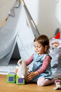 童年，休闲和人的概念—快乐的小女婴在家里玩软玩具。快乐的女婴玩软玩具在家里