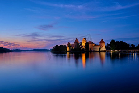 凯夫拉尔摄影照片_特拉凯岛城堡在加尔夫湖照明在黄昏反射在宁静的水，立陶宛。Trakai Island Castle in Lake Galve，立陶宛
