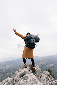 后视图妇女提高她的手臂站在山顶