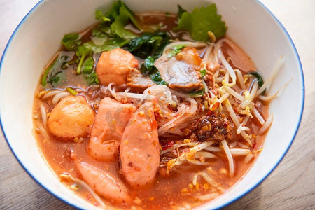 猪心汤面摄影照片_红色汤面猪肉与红色烤猪肉和豆芽蔬菜在汤碗在木桌，顶视图泰国和中国亚洲食物