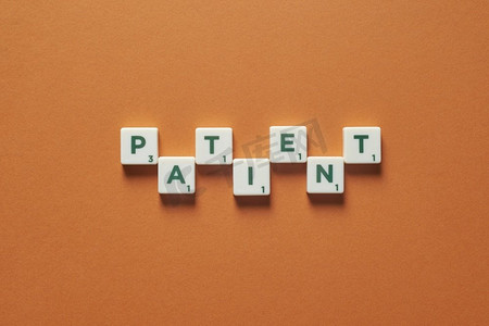 病人字形成的拼字砖在棕色背景。医学检查和身体健康意识。病人是由瓷砖形成的。