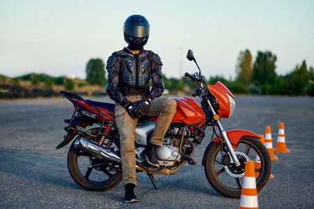 男學生在摩托車上擺姿勢,騎在摩托車學校的 motordrome 上.