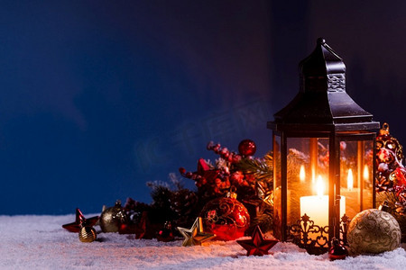 燃烧的圣诞灯笼和冷杉树装饰在雪地上的蓝色背景和复制空间。雪中的圣诞彩灯