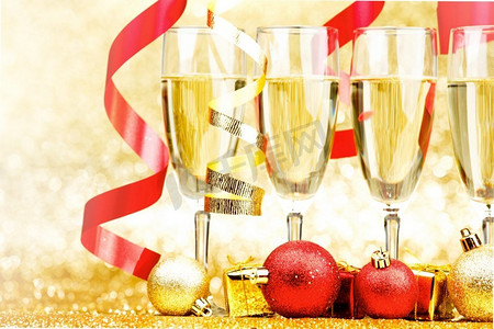 香槟酒和红丝带的玻璃在金色背景。香槟和缎带