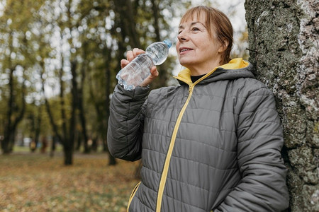 户外运动后喝水的侧视老年女性