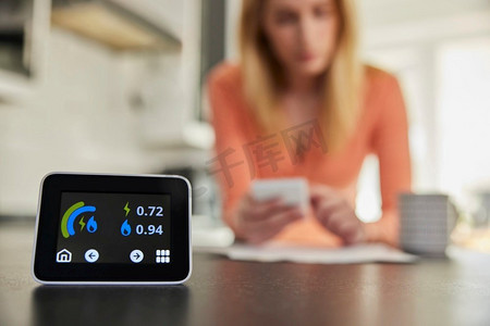 关闭智能能源表在厨房测量电力和天然气使用与妇女看账单与计算器