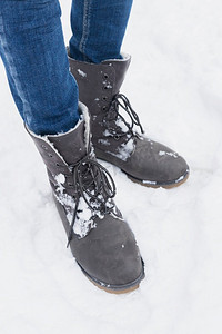 冬季女靴主图摄影照片_低部分妇女站在与冬季靴雪