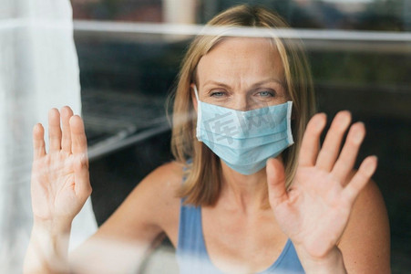 一名女子在隔离期间戴着医用口罩往窗外看2