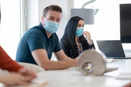 真正的商务人士在明亮的办公室就冠状病毒新常态开会，戴上防护医用口罩并保持距离