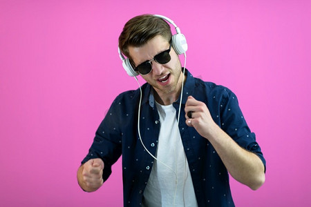 该家伙戴着眼镜和耳机，而跳舞和有乐趣孤立在粉红色的背景