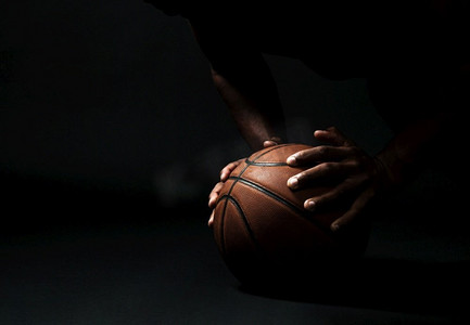 俯卧撑摄影照片_非洲裔美国篮球运动员的裁剪照片，做俯卧撑练习在球，在黑色背景
