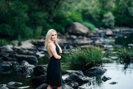 石质河岸上一位穿着黑裙子、蓝眼睛的金发女孩