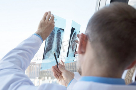 医疗窗口摄影照片_两名医生在诊所的窗口检查x光片。检查X光片的医生