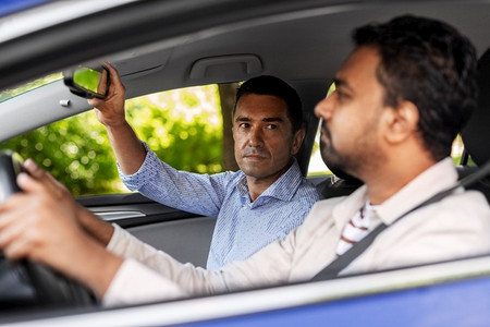 驾驶员课程和人的概念—人和驾驶学校教练调整汽车镜子。汽车驾驶学校讲师教男司机