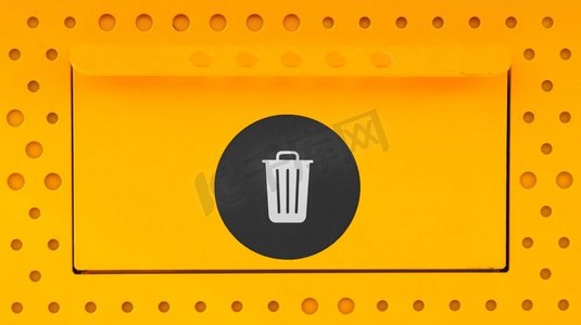 地球贴纸摄影照片_黄色垃圾可以在灯光上贴上黑色贴纸进行特写。垃圾桶打开时，在带有图标的金属表面上关闭并点亮。