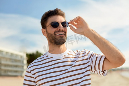 海边风格摄影照片_暑假和人的概念—年轻人的肖像在海滩太阳镜在塔林，爱沙尼亚。年轻人在夏天的海滩太阳镜