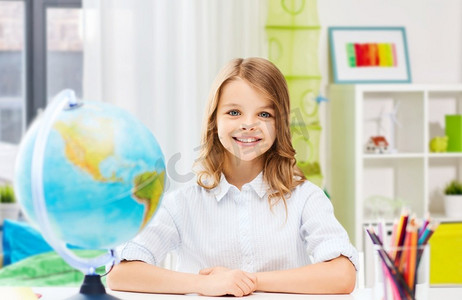 教育和学校概念—愉快的微笑的学生女孩与地球仪在家庭背景快乐的微笑的学生女孩与地球仪在家里