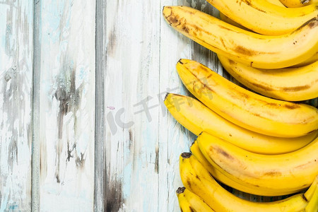 轻饮食摄影照片_很多新鲜多汁的香蕉在一个轻的木背景。很多新鲜多汁的香蕉。