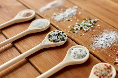 食物，烹饪和不健康的饮食概念-木桌上加盐和香料的勺子。木桌上放有盐和香料的勺子