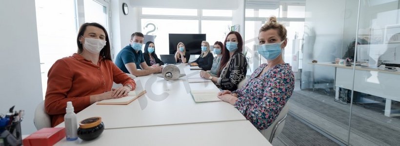 真正的商务人士在明亮的办公室就冠状病毒新常态开会，戴上防护医用口罩并保持距离