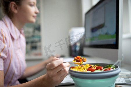 员工电脑摄影照片_办公室女员工在办公桌前吃健康素食午餐