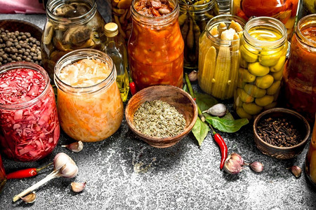 泡菜腌制摄影照片_玻璃罐里用香料腌制的蔬菜。在一个乡村的背景下。玻璃罐里用香料腌制的蔬菜。