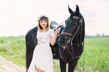 丝质裙子摄影照片_女孩红色的嘴唇在白色的裙子附近的一匹黑马