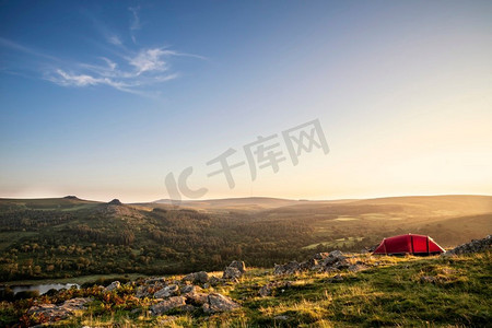野生露营在英国乡村的美丽图象在惊人的夏天日出与太阳的温暖的辉光照亮风景