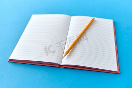 教育和实物概念-打开笔记本或日记，用铅笔在蓝色背景上。打开带蓝色背景的铅笔笔记本
