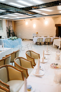 餐厅宴会厅的新人主席团用蜡烛和绿色植物装饰，紫藤悬挂在天花板上，
