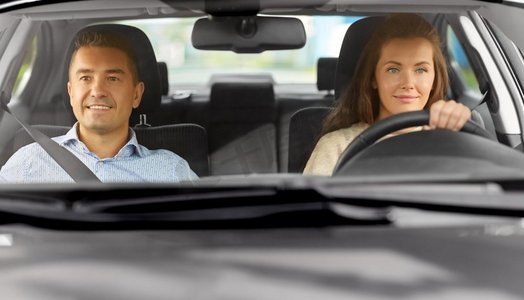 驾驶员课程和人概念—汽车驾驶学校讲师教年轻女子驾驶。汽车驾驶学校教师女教师