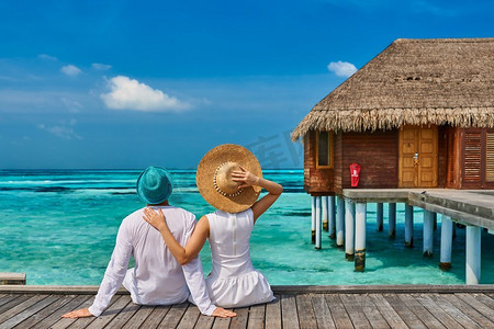 夫妇在白色的热带海滩码头附近的水别墅在马尔代夫