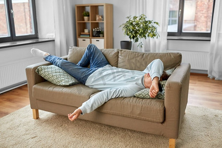 人，无聊和抑郁的概念—无聊或懒惰的年轻人躺在沙发上在家里。无聊或懒惰的年轻人躺在家里的沙发上