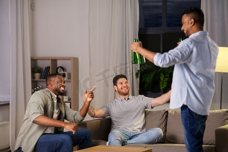 友谊、休闲和人的概念—快乐的男性朋友晚上在家喝啤酒。快乐的男性朋友喝啤酒在家里晚上