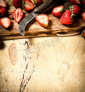 用木板上的旧刀切草莓片。在木制背景上。用木板上的旧刀切草莓片。