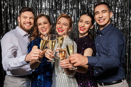 圣诞摄影照片_庆祝和假日概念—快乐的朋友在聚会上碰杯香槟。朋友在聚会上喝香槟酒