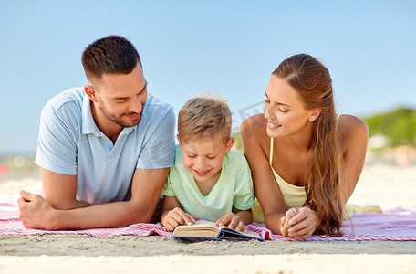 家庭，休闲和人的概念—快乐的母亲，父亲和儿子奠定和阅读书在夏季海滩。快乐的家庭阅读书在夏季海滩
