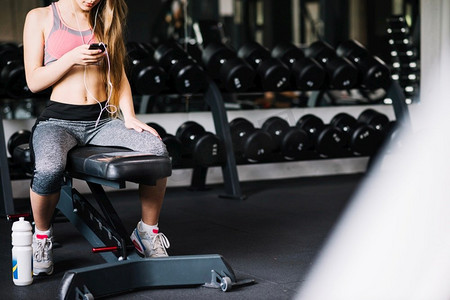 坐在健身房里的手机女孩高分辨率照片。坐在健身房里的手机女孩高品质的照片