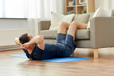 运动，健身和健康生活方式概念—男子在家里做腹部运动。男人做腹部运动在家里