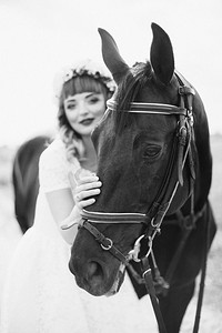 女孩红色的嘴唇在白色的裙子附近的一匹黑马