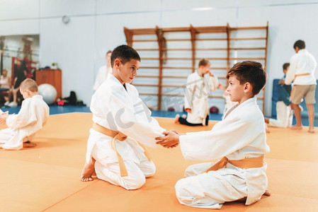 穿制服的小男孩练习柔道。年轻战士在体育馆训练，武术防御。穿制服的男孩练习武术