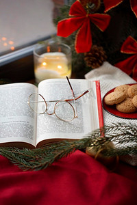 阅读，假期和休闲概念—关闭打开的书和眼镜在圣诞节在家里。关闭打开的书和眼镜在圣诞节