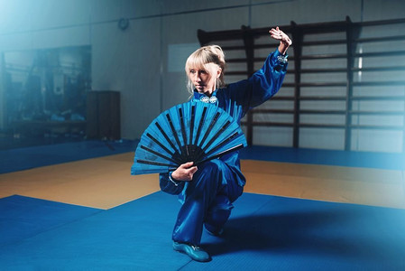 女武术大师与扇，武术。穿蓝色衣服的女人在战斗训练。女武术大师与扇，武术
