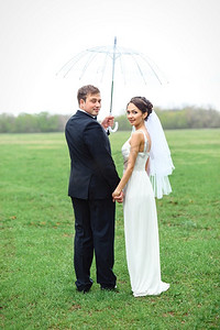 新娘和新郎在下雨的婚礼当天走在雨伞下