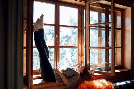 窗户雪景摄影照片_女孩在靠窗的房子里俯瞰着雪景