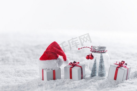 圣诞装饰品上有红色的蝴蝶结，圣诞老人的帽子，白色的文字空白处。雪中的圣诞装饰